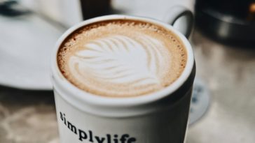 Einfacher Milchkaffee in einer Tasse mit der Aufschrift simplylife