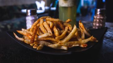 Frittierte Pommes auf einem schwarzem Teller