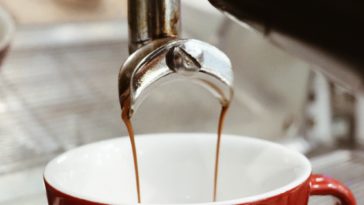Kaffeetasse unterm Kaffeevollautomat, Kaffee fließt in die Tasse