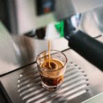 Kaffepadmaschine mit einem Glas Espresso darunter