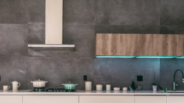 Rustikale Küche mit Holzelementen, blauen Lichtern und silbener Dunstabzugshaube