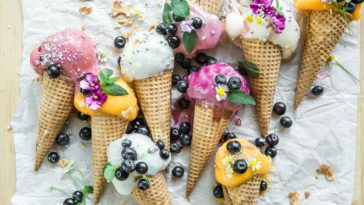 Verschiedene Eissorten in Waffeln mit Blaubeeren und Zuckerkugeln auf einem Tisch